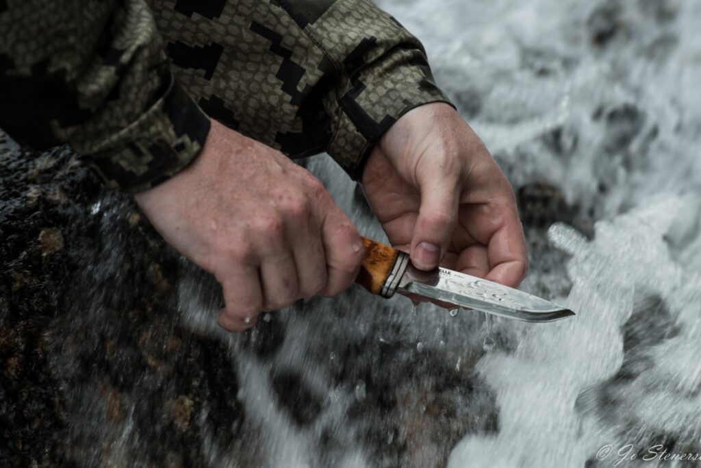 closeup knife in hands with a waterfall in the background