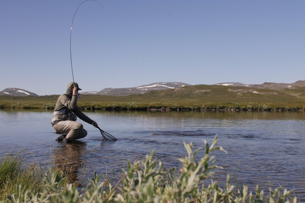 a man fishing in a lake catching a salmon